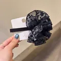 Primer plano de una pinza para el pelo con flor de encaje negro sobre tarjeta blanca - Clips de resorte / Negro