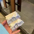 Douces barrettes bleues à pois noirs avec des nœuds en satin blanc sur une carte - Bleu