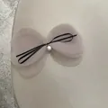 Detailed view of layered pink mesh bow hair clip with black ribbon and white pearl accent - Light Gray