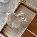 Detalle de las capas de organza y perlas en el elegante pasador de pelo - Beige