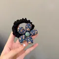 Floral fabric hair scrunchie with blue pattern and bead center held by a hand - Blue Floral