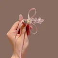 Pink floral bead hair clip with ribbon and white shell flower detail held by hand - Pink