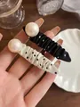 Detail einer Haarklammer aus Stoff mit schwarz-weißen Punkten und einer großen Perle - Schwarz mit weißen Punkten