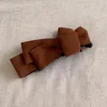 Macro shot of vintage brown suede bow banana clip with elegant layered fabric detail - Brown