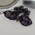 Detalle de coletero de cuadros blancos y negros con lazo y colgante dorado elegante - Cuadros Negros