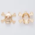 Vintage gold skull and crossbones metal pendants with embossed textures on white background - Light gold
