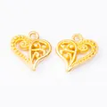 Detailed close-up of vintage heart charms with golden hollow floral scroll patterns - Gold