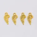 Makroaufnahme von vier goldenen Flügelanhängern mit feinen Federtexturen für DIY-Schmuck - Antikgold
