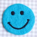 Sky blue wool felt coaster featuring a minimalist black smiley face pattern - Dark Blue