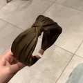 Primo piano di cerchietto in raso verde oliva con nodo e finitura in seta liscia - Marrone