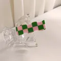Primer plano de una pinza para el cabello ondulada con cuadros rosas y verdes de acetato - Rejilla Verde y Rosa