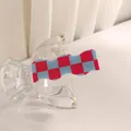 Detalle de una pinza para el pelo ondulada de cuadros rojos y azules sobre vidrio - Rejilla Roja y Azul
