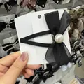 Elegante fermaglio per capelli a fiocco nero con perla su cartoncino bianco - Nero