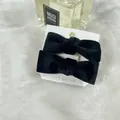 Elegant pair of black velvet bow hair clips presented on a display card for women - Black