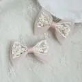 Detailed view of pink satin hair bows with white floral lace embroidery on fabric background - Pink