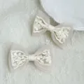 Detail of elegant white lace bow hair clips with intricate floral embroidery and tulle - White