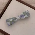 Detailed close-up of a floral embroidered bow hairpin with vintage jacquard fabric texture - Bow Flower Hair Clip