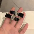 Pair of black satin bow hair clips with oval rhinestones over an open book - Black