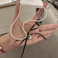 Close-up of pearl necklace featuring a silver heart pendant and black ribbon bow - White Pearl Black Bowknot