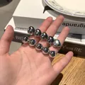 Dettaglio di fermagli per capelli argentati con cuore e perle tenuti in mano - Stile Argento a Cinque Cuori