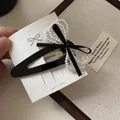 Détail d'une barrette à cheveux nœud en velours noir et perles sur une carte - Style Noeud en Dentelle / Noir