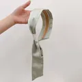 Dettaglio del cerchietto in raso verde chiaro con nastro lungo e fodera antiscivolo - verde chiaro