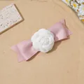Vue détaillée du nœud en satin rose avec une fleur de camélia blanche sur un plateau - Camélia Rose