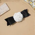 Détail d'une élégante pince à cheveux avec nœud en satin noir et fleur de camélia blanc - Camélia Noir