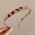 Nahaufnahme des bernsteinfarbenen Haarreifs mit Herzmuster und OXO-Buchstabendesign - Graues Leopard Dünnes Haarband
