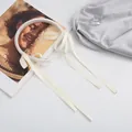 Detalle de diadema de satén crema con elegantes cintas largas y fluidas en vista plana - Blanco