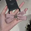 Dettaglio ravvicinato dell'elastico per capelli con fiocco di raso rosa e cristallo - Rosa Con Cuore Di Strass