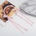 Detalle de la diadema de satén rosa con cintas largas y finas sobre fondo blanco - Rosa