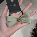 Dettaglio di elastico per capelli in raso verde salvia con cristallo a forma di cuore - Ciano Con Cuore Di Strass