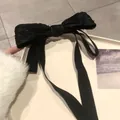 Close-up of black lace bow hair clip with long ribbon streamers and elegant texture - Black