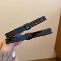 Detail of glossy black bow-shaped hair clips made of high-quality acrylic on hand - Black