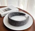 Detailed shot of grey wool headband with handmade label on white ceramic plate - Gray
