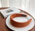 Close-up of caramel wool headband with handmade label on ceramic plate background - Dark Coffee