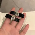 Pair of elegant black satin bow hair clips featuring large oval crystal embellishments - Black