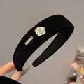 Detailed close-up of a velvet headband featuring a white camellia and gold handmade tag - Wide Edge Style (A395) / Black