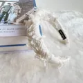 Detailed view of beige tweed headband with fringe edges and handmade label on soft fur - White Grid