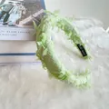 Detail of green and white tweed headband with soft feathers and handmade label - Green Plaid