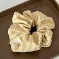Close-up of beige corduroy scrunchie texture with Mared label on dark tray - Yellow