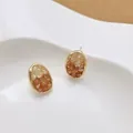 Ovaalvormige kristallen oorknopjes met kleurverloop en goudrand op een houder - Gouden glinsterende diamant oorknopjes