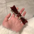 Détail de la barrette à nœud en velours rouge foncé avec tweed et pendentif doré chic - café