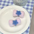 Close-up of pink velvet bow hair clips with blue stars in a ceramic dish display - Purple Blue Star