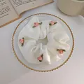 Dettaglio di uno scrunchie in chiffon bianco con rosa di nastro rosa su un piatto di vetro - Rosa 3D (Bianco Latte) / crema