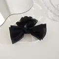 Detail of a black organza double-layered bow scrunchie on a white ceramic tray - Black