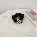 Close-up of black satin scrunchie with a checkerboard square charm on paper - Black Square