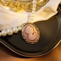 Detail view of a vintage cameo pendant featuring a woman's profile and elegant pearls - Pink