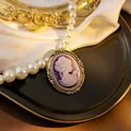 Detail of vintage purple cameo brooch with golden frame and large white pearls - Purple